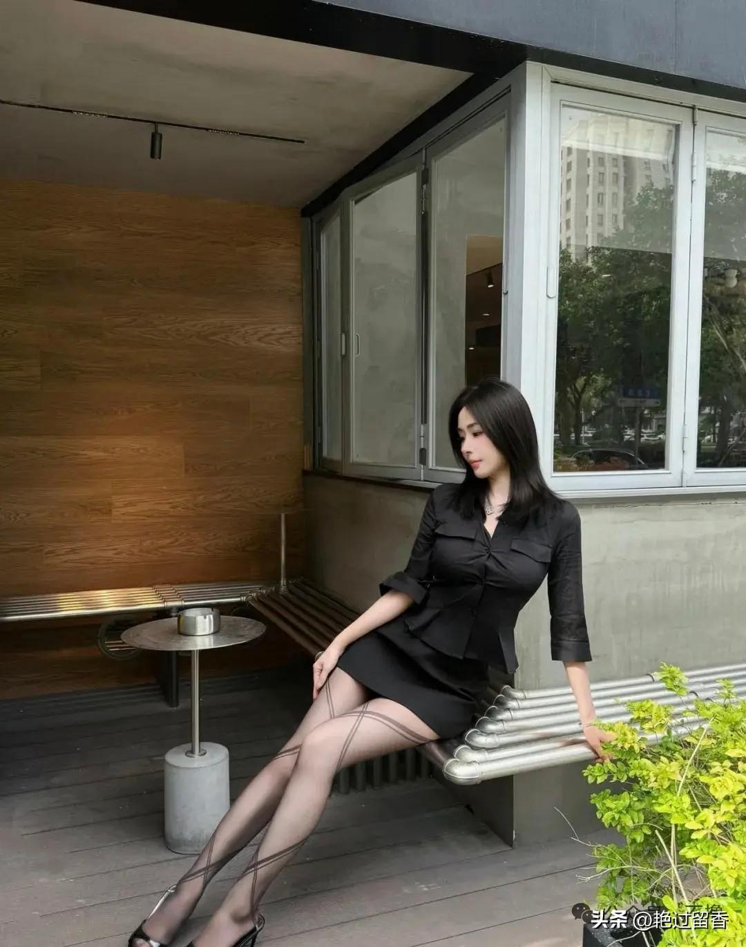 都市女性优雅姿态，黑裙与绿植相映成趣。