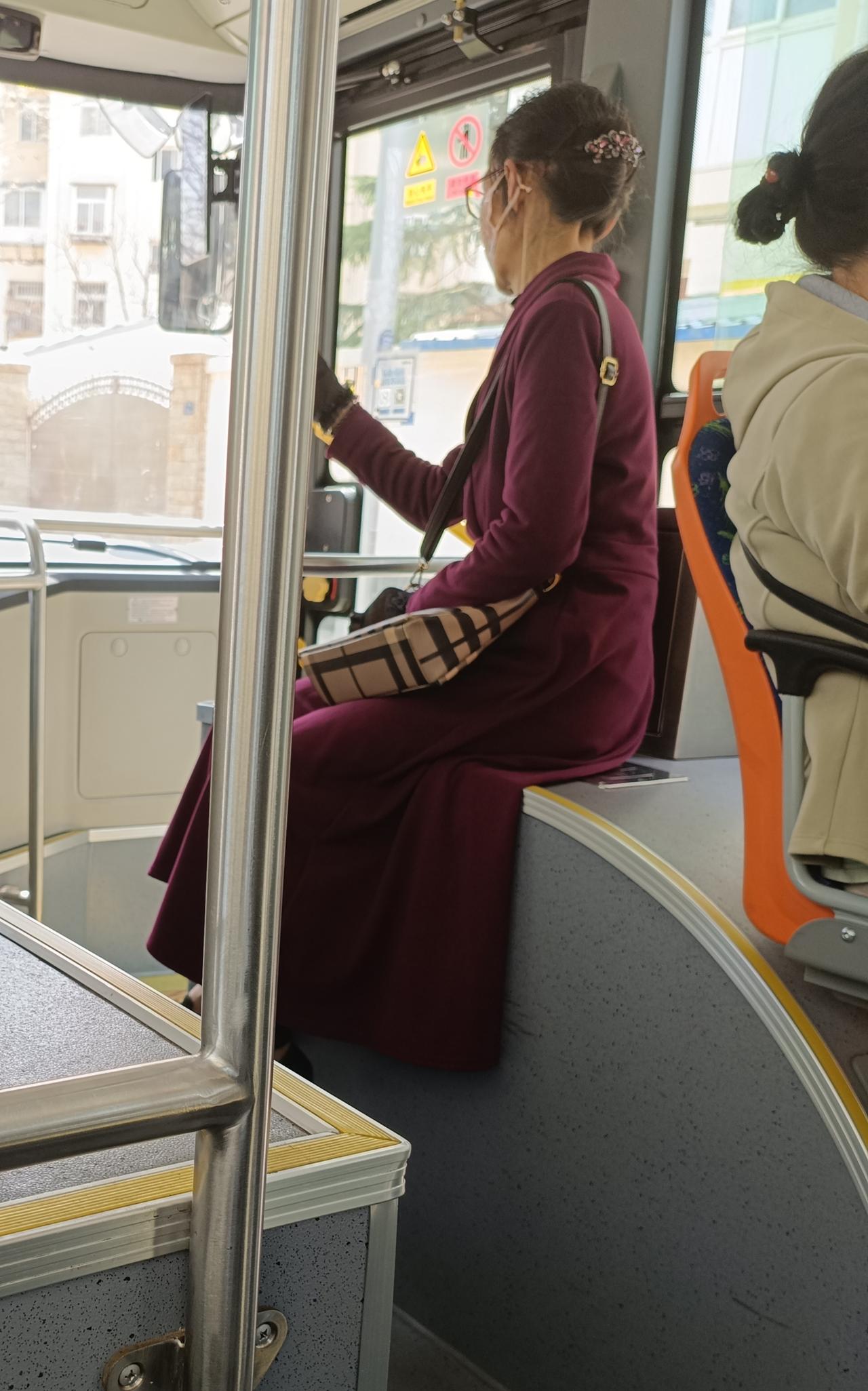 在公交车上看到一位女士，从侧面看去应该也不是太老，身着紫红色的连衣裙，背着一个俨