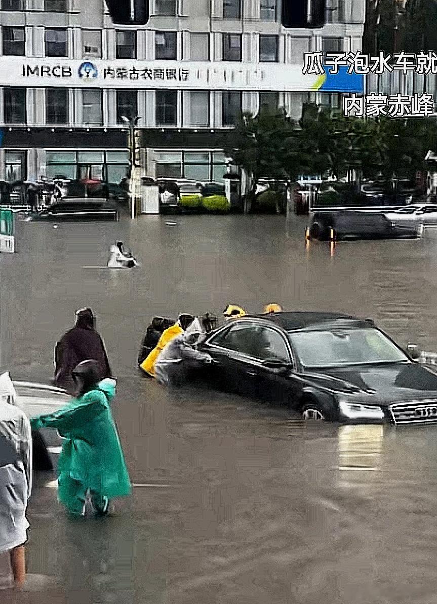 㓎水的马路上，一辆电动车在水里游 
