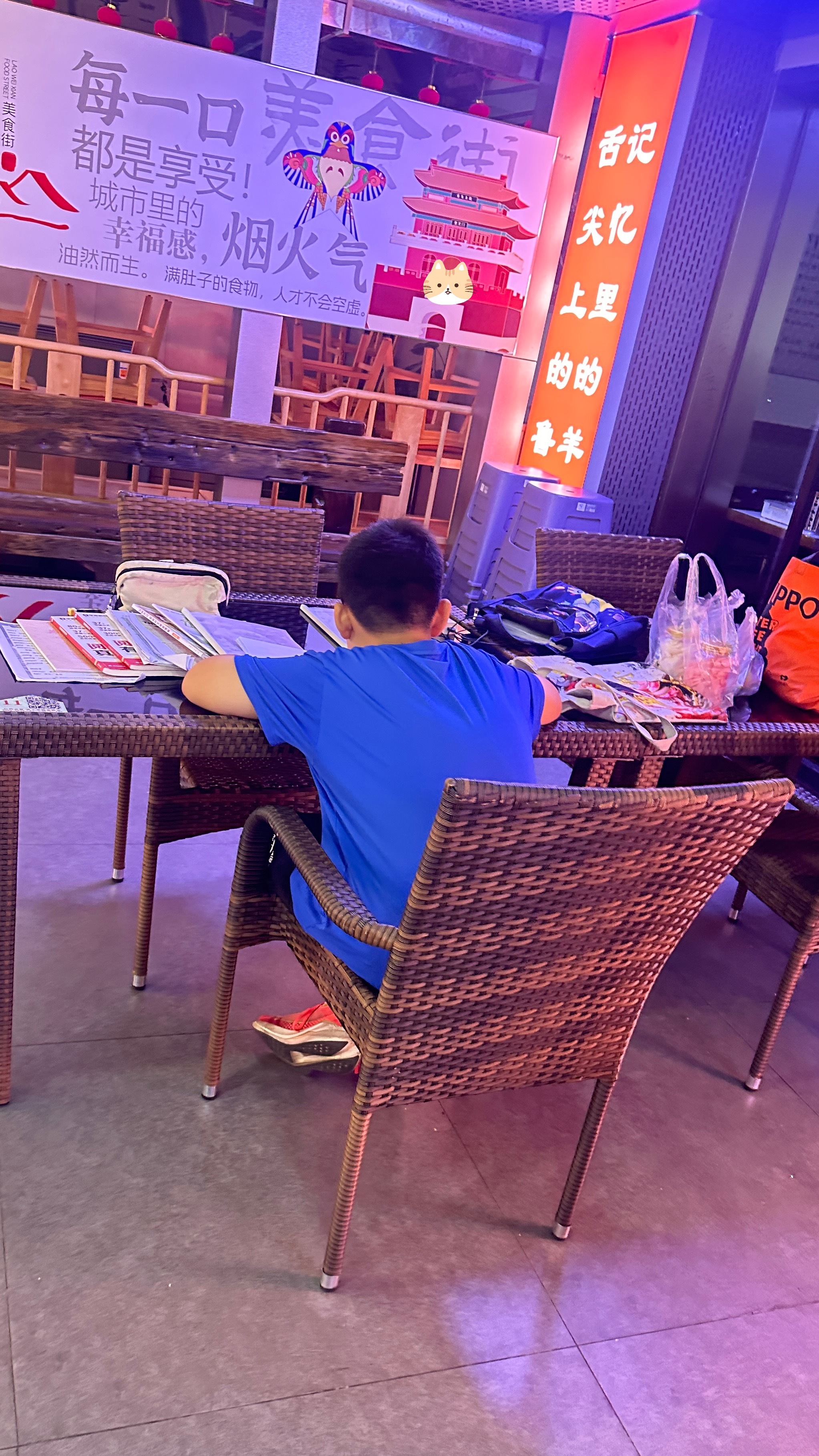 早上送完润润去美食街吃完早饭看到一个在认真伏案写作业的小男孩吃早饭的人来来往往，