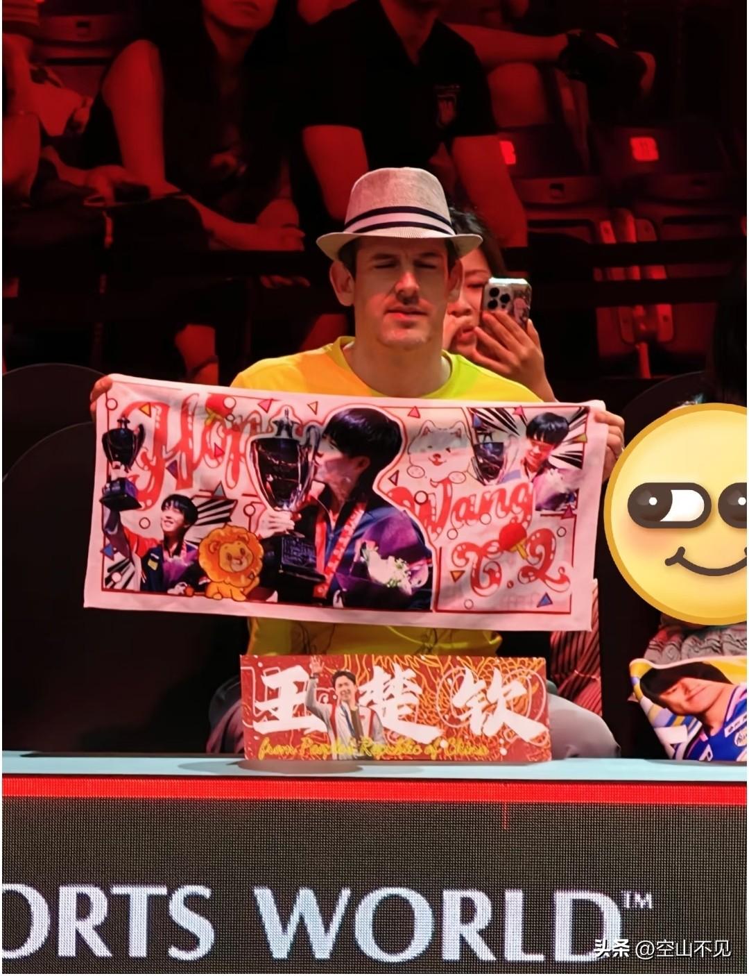 好搞怪的洋薯条
穿着黄T恤，戴着礼帽，那么显眼。坐得正正经经，手幅又举得高高的，