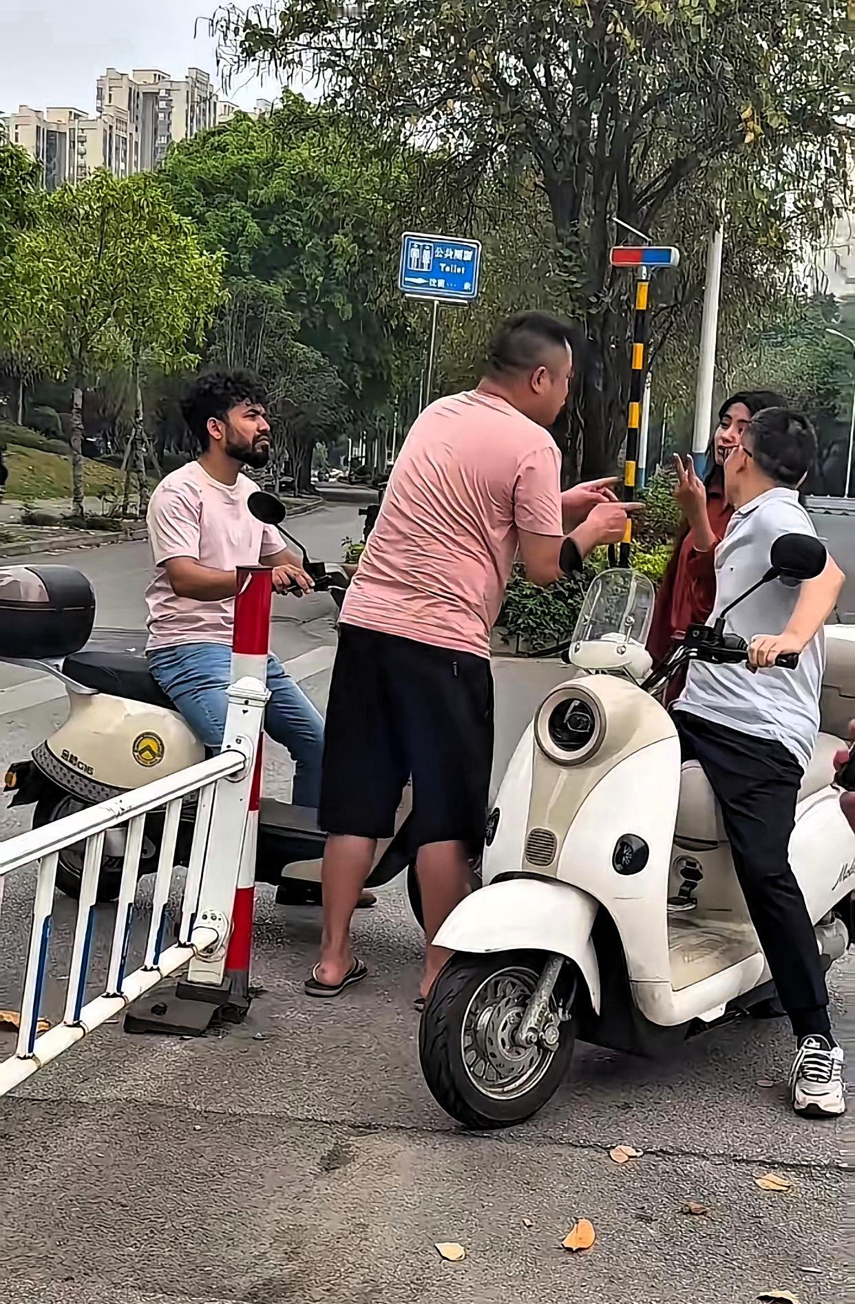 近日广西柳州，一位粉衣大哥骑着电动车在路上，结果被一个骑着电动车的外国人别车，