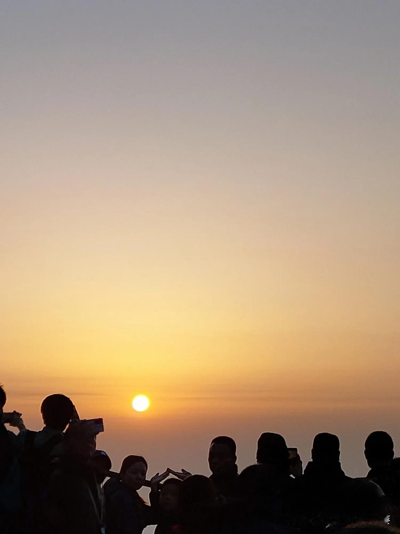 记得那天和一群人挤在山顶等日出，风有点凉，大家都缩着脖子。
 
等那团小太阳从天
