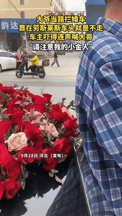 河北婚礼清晨，婚车队刚动。一位大爷突然冲上前，后背贴紧劳斯莱斯“小金人”，伸手要
