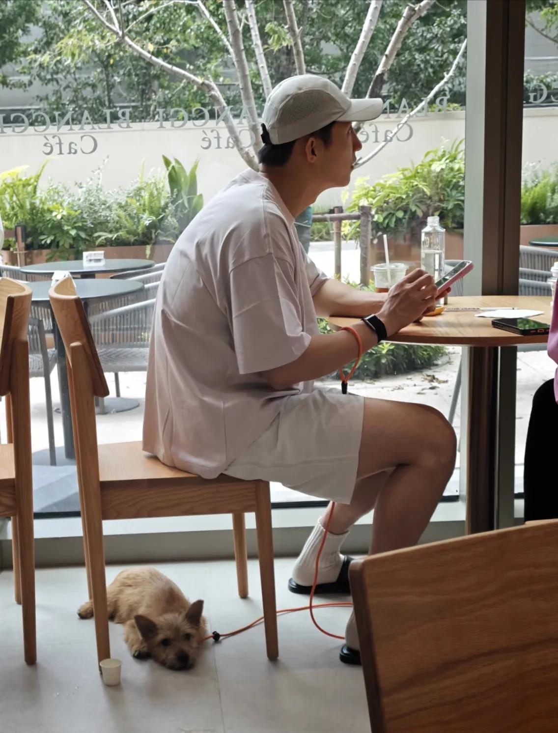 黄景瑜和朋友现身上海咖啡店喝咖啡，他和朋友一边聊天一边玩手机，他的小狗就静静地在