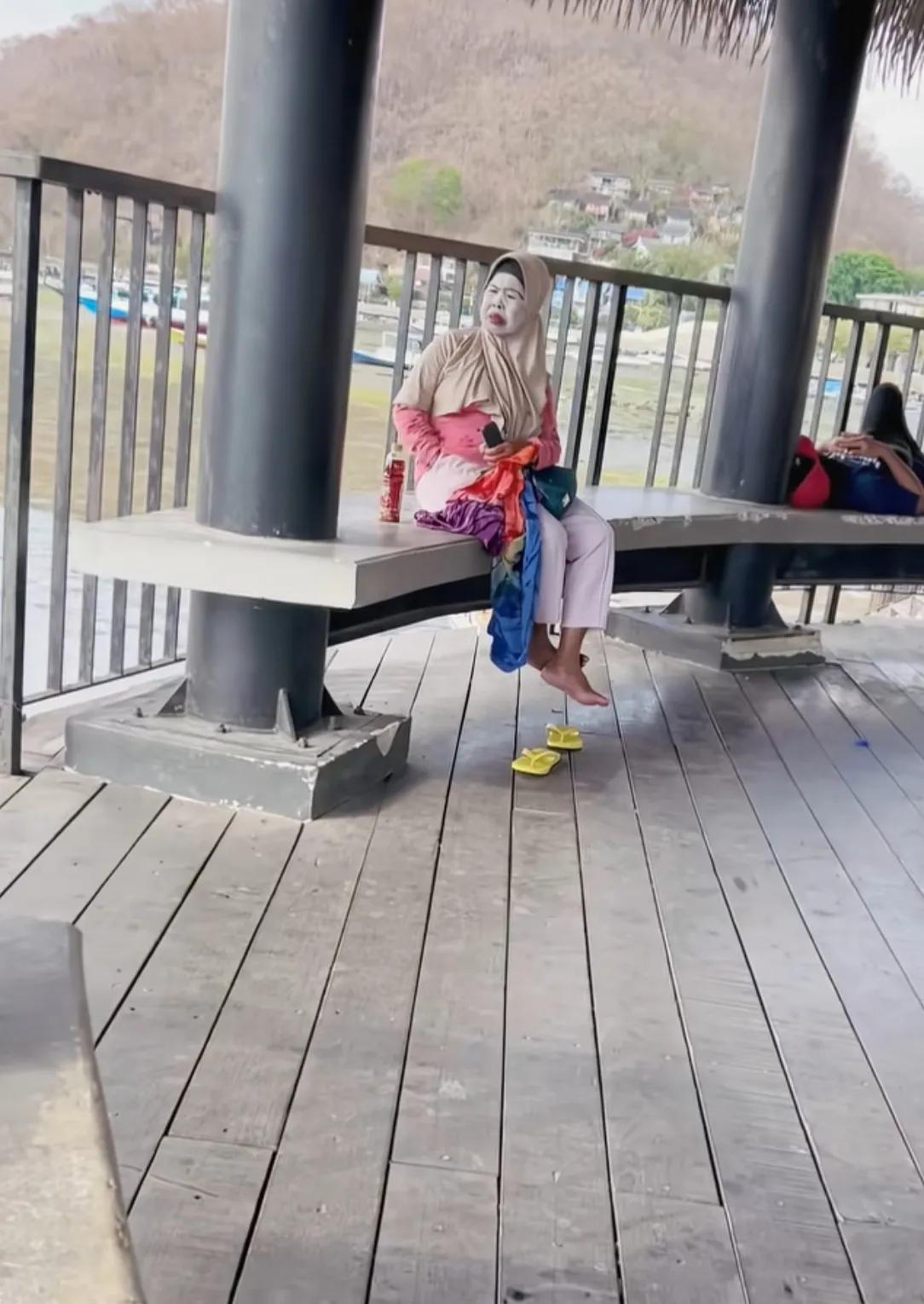 海边亭子偶遇这位阿姨，脸上厚厚一层防晒泥，红唇特别显眼。看着打扮精致，悠闲坐在那