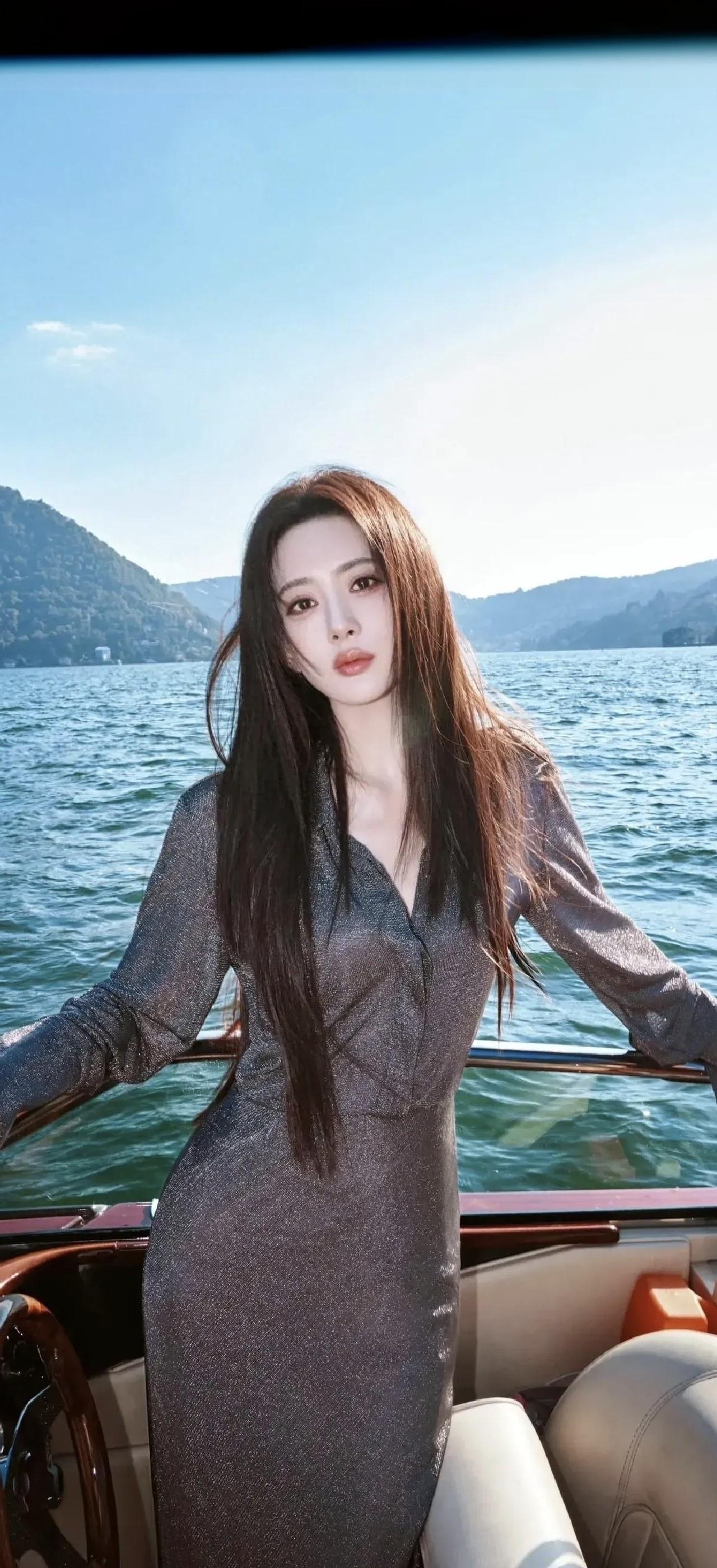 一个美女在海边的游艇上拍照。