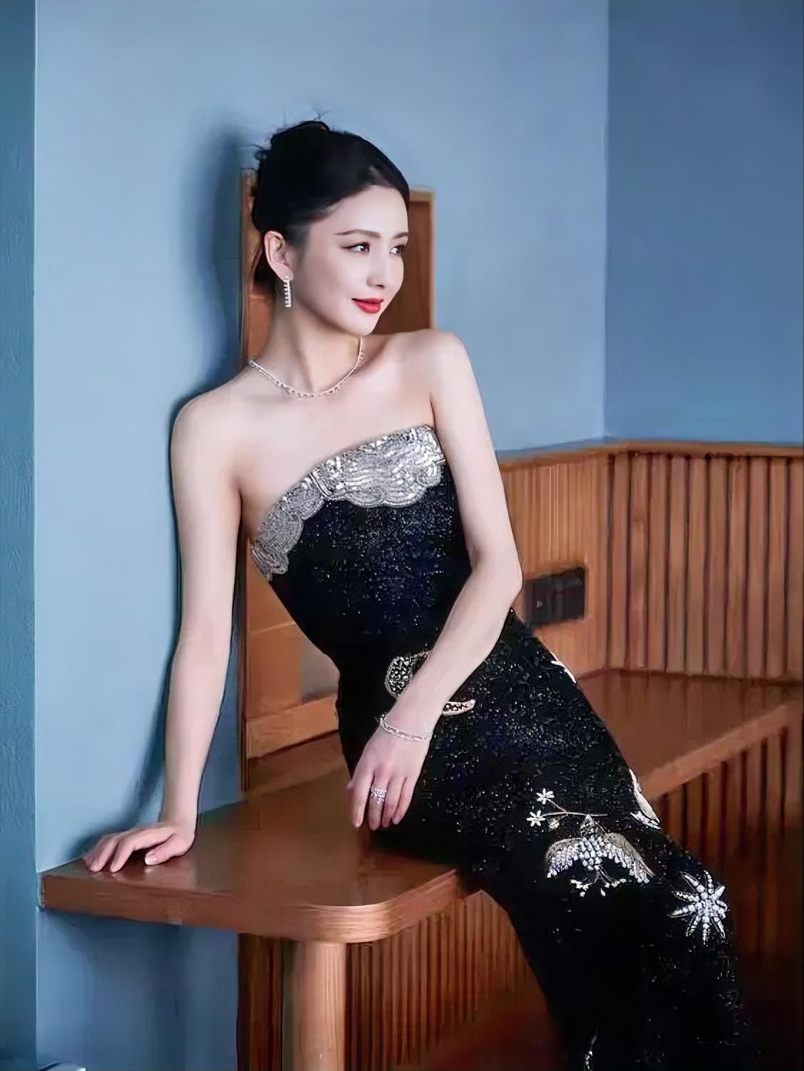 蓝光轻落，她便成了夜色里的诗。

黑裙缀银，肩颈如画。

倚着木栏，笑意温雅。