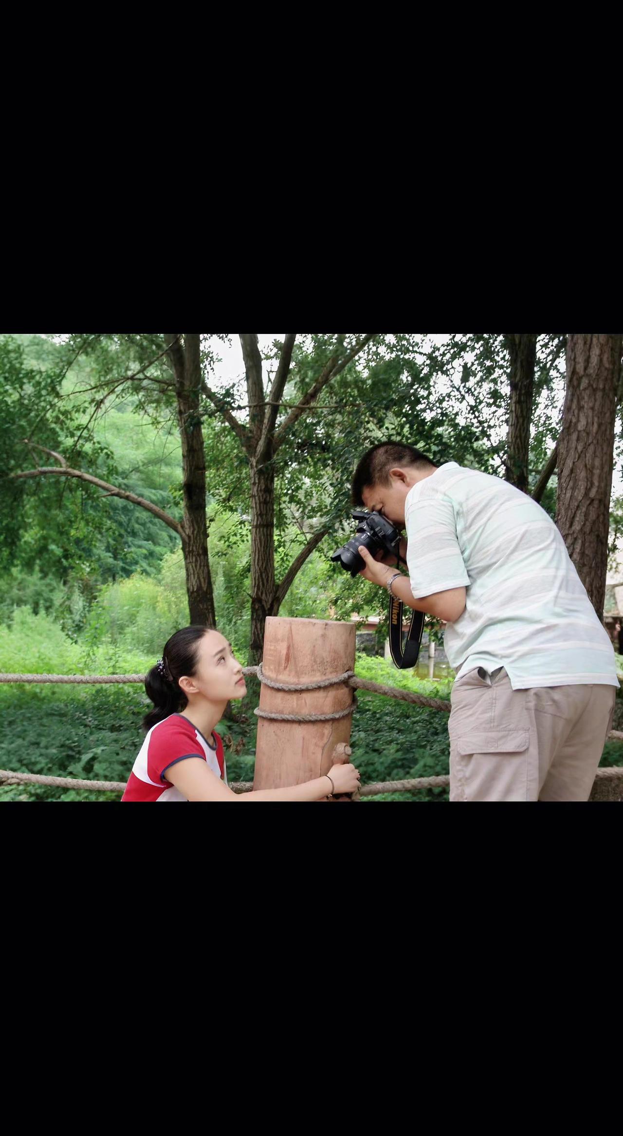 🌳镜头框住夏光，树影漏下碎金✨。她吻木墩年轮，他定格时光褶皱⏳。自然是最好的打