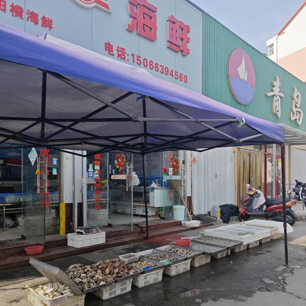 从<青岛海滨超市>出来，大门口处的东边即是一<田横海鲜小超市>。
小超市的门前摊