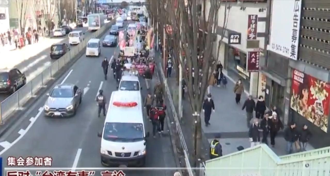 东京街头，大批民众走上街道参与集会，道路上警车、救护车随行，现场有警力维持秩序。