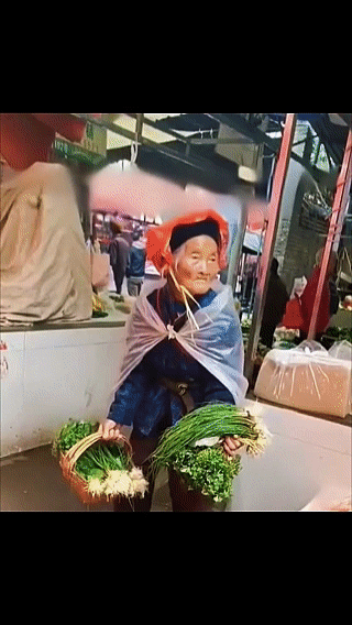 老奶奶七十多岁，孤零零的站在雨中卖菜，一把葱、一把青菜就是她的生活。
看到这一幕