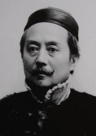 1871年，德国的一辆火车上，辜鸿铭手拿报纸，倒着在看。两名德国小伙在一旁用德文