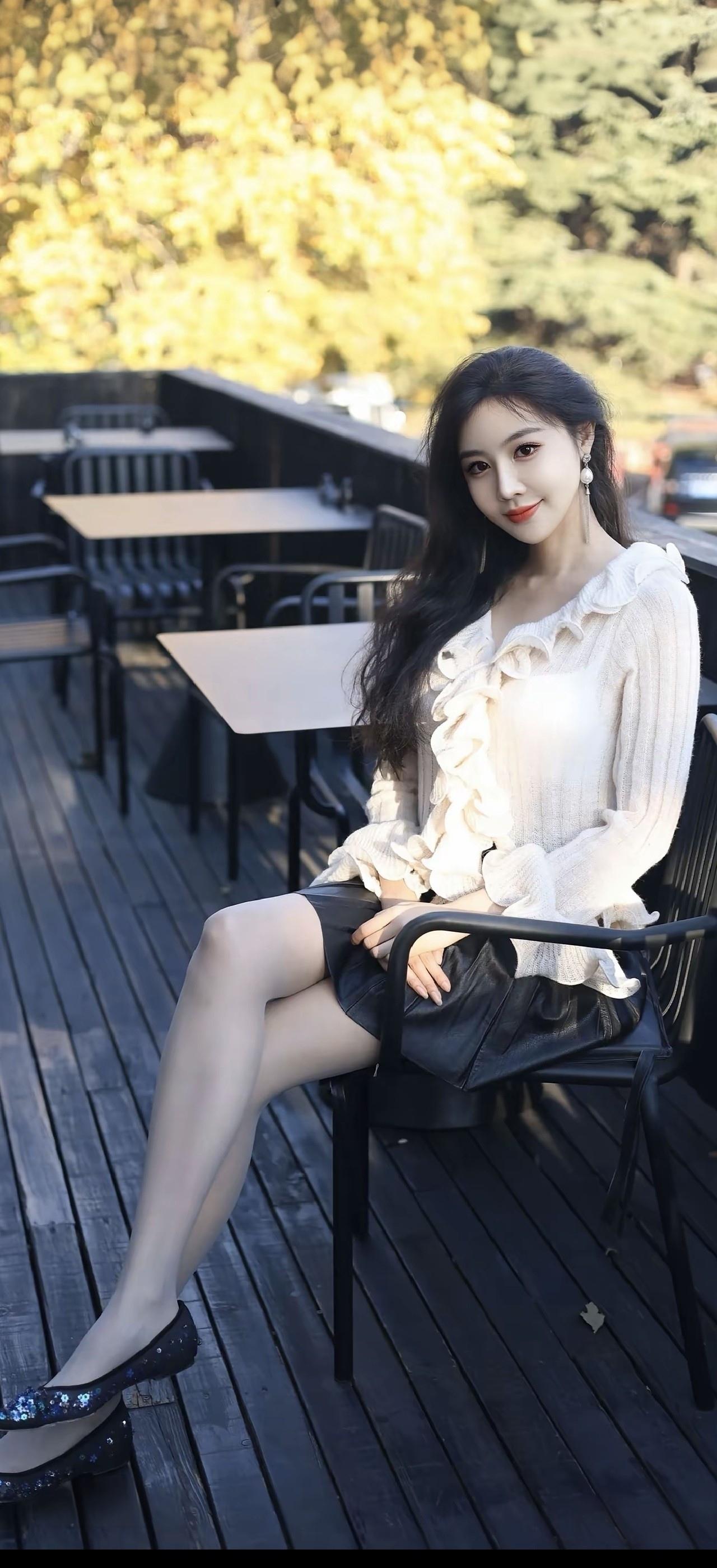 一个美女坐在户外的咖啡馆里。