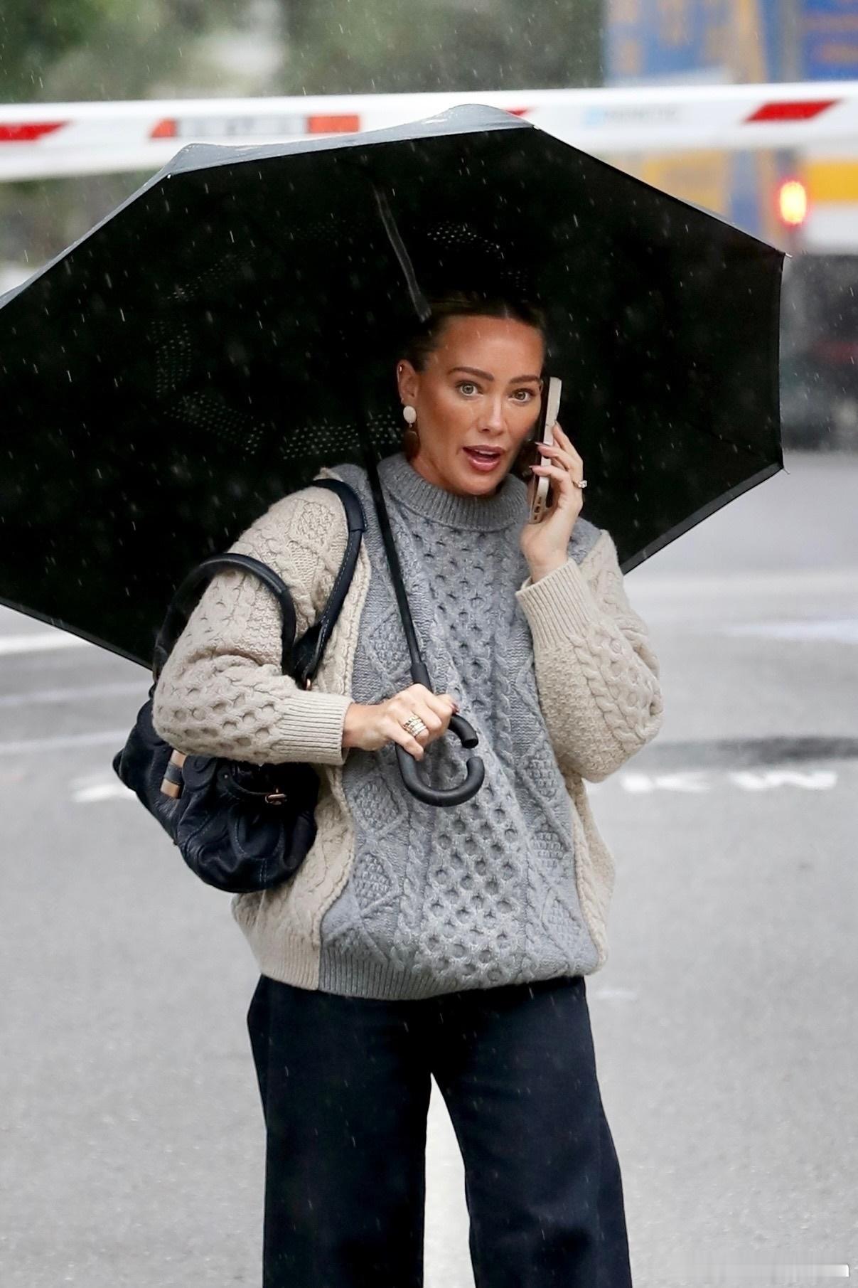 希拉里达芙在洛杉矶外出，当地下起了雨，达芙撑着伞前往购物 