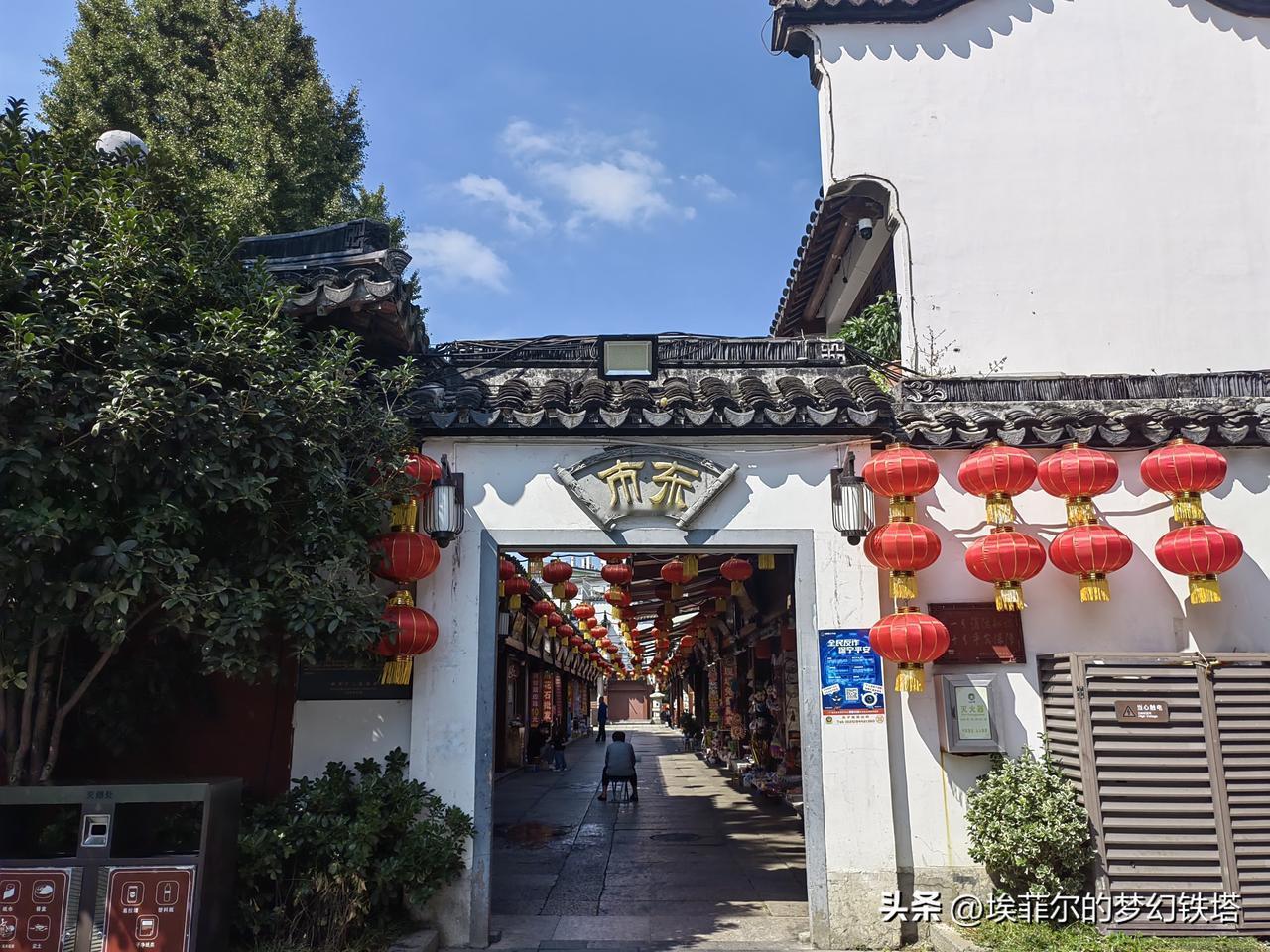 白墙黛瓦间悬着一排排红灯笼，像一串未拆封的旧梦。门楣上“东市”二字古朴沉静，仿佛