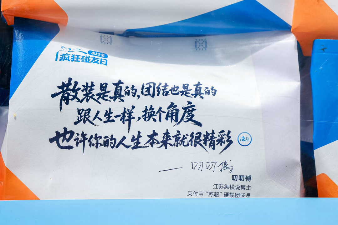 百店发支付宝助威袋为南京队加油支付宝疯狂碰友日满满一车“苏超”助威袋来到南京，街