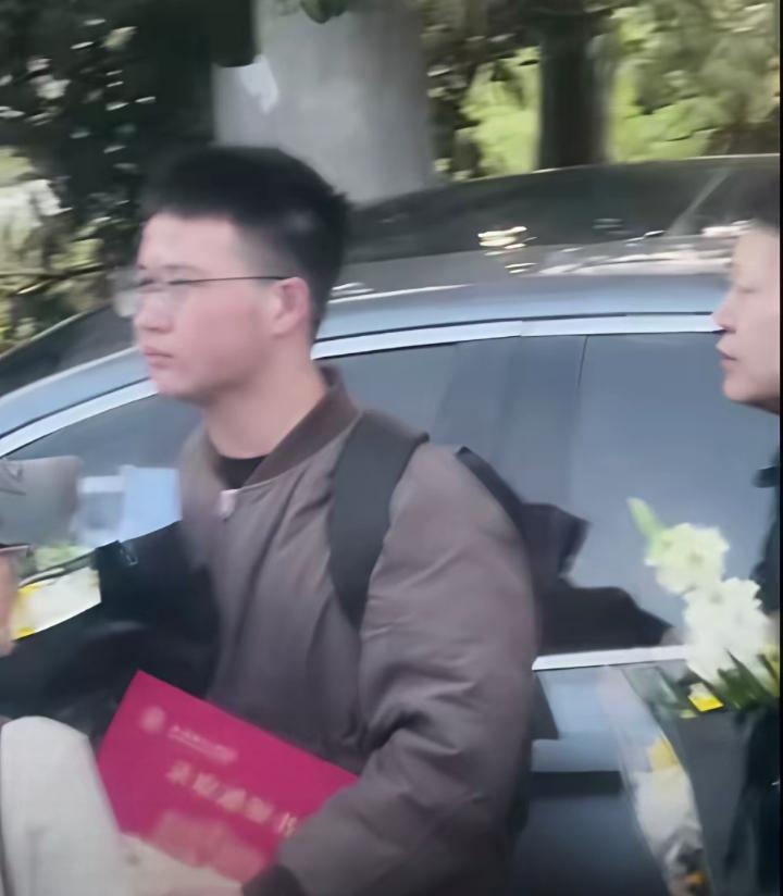 送行张雪峰的现场，这一幕直接看哭所有人。一个男孩他背着双肩包，一手捧着鲜花，一手
