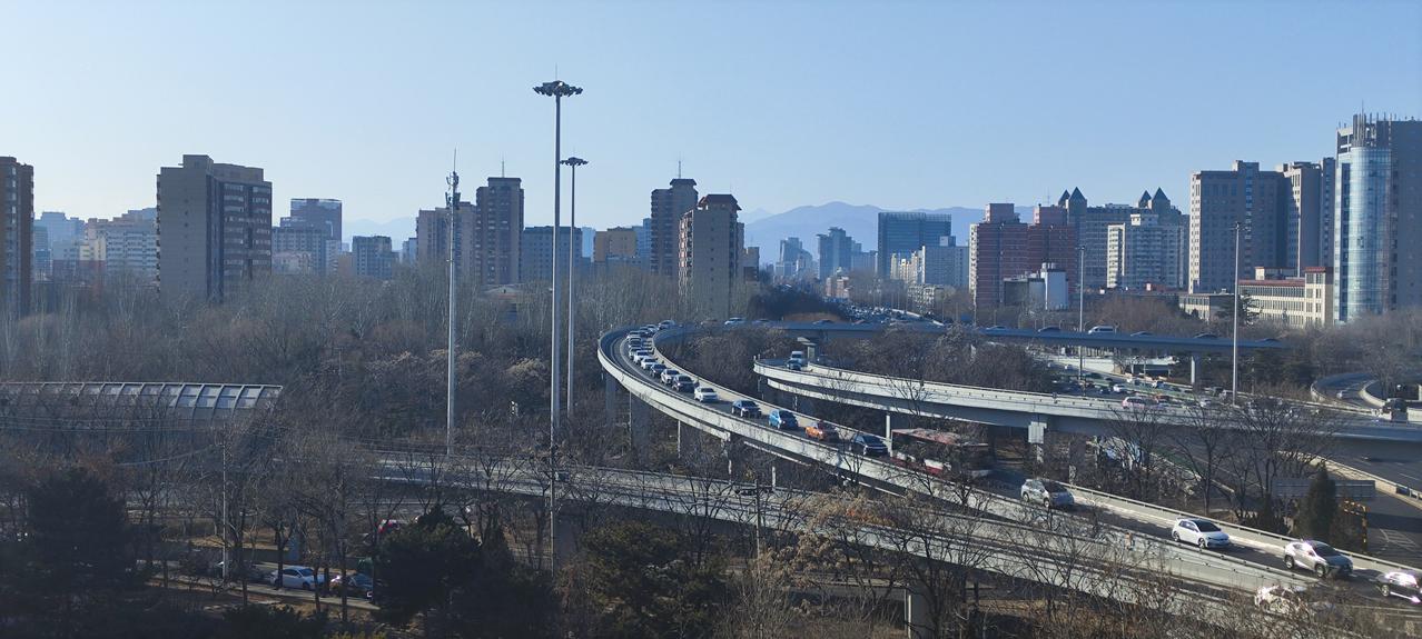 北京冬日一个平常午后，城市天际线交织高架上的车流...