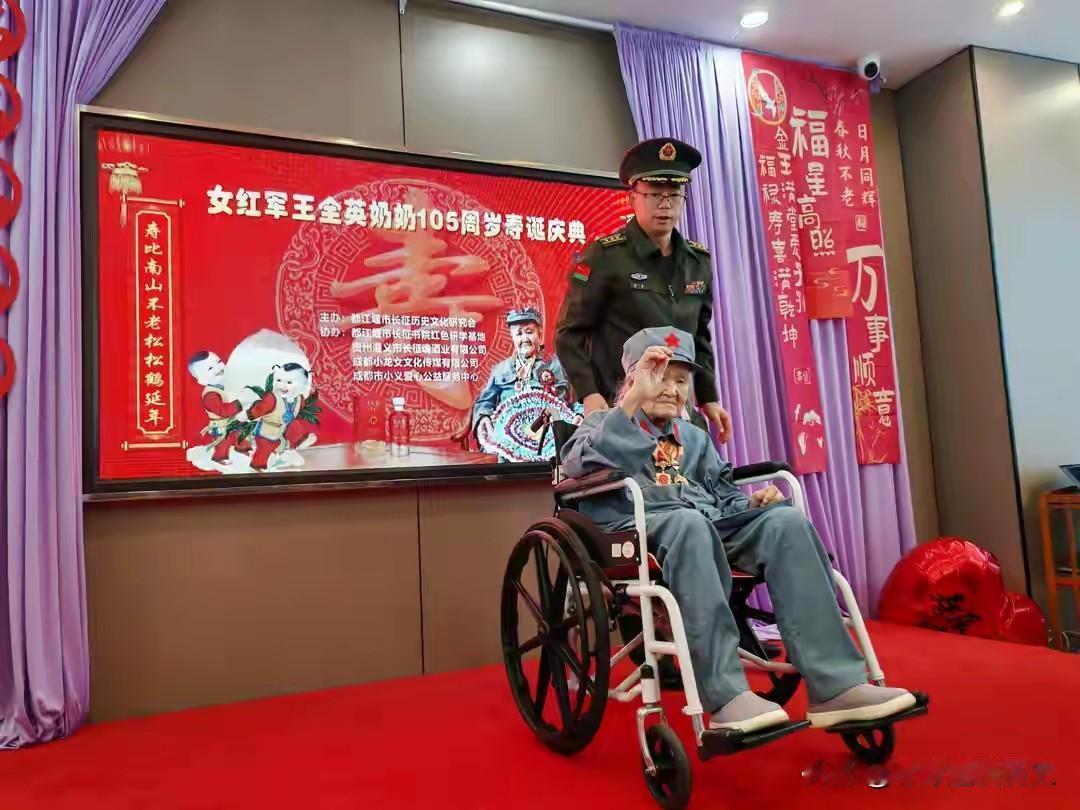 这场寿典定格了百岁女红军王全英105岁的珍贵时刻。
老人端坐在轮椅上，身着复刻的