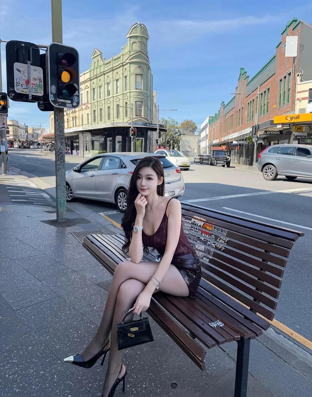 都市街头的时尚少女，优雅地坐在长椅上，享受着阳光。