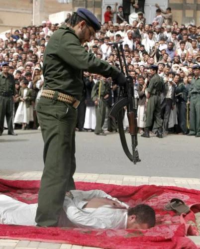 2009年，也门街头，执行死刑的一幕，镜头中的男子趴在一张红地毯上，一名士兵手拿