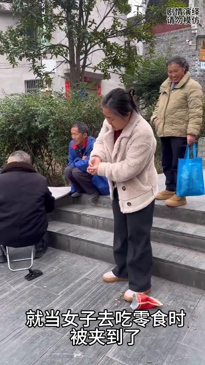 女子吃零食时看下象棋，男子把夹子放零食里整蛊她。
女子正在吃零食时，就当她看别人