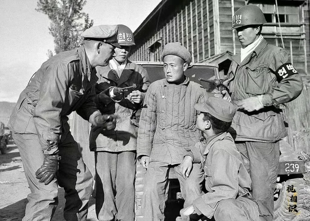 1950年，韩国，美韩士兵正在审问一名战俘，这名战俘不知道是来自朝鲜...