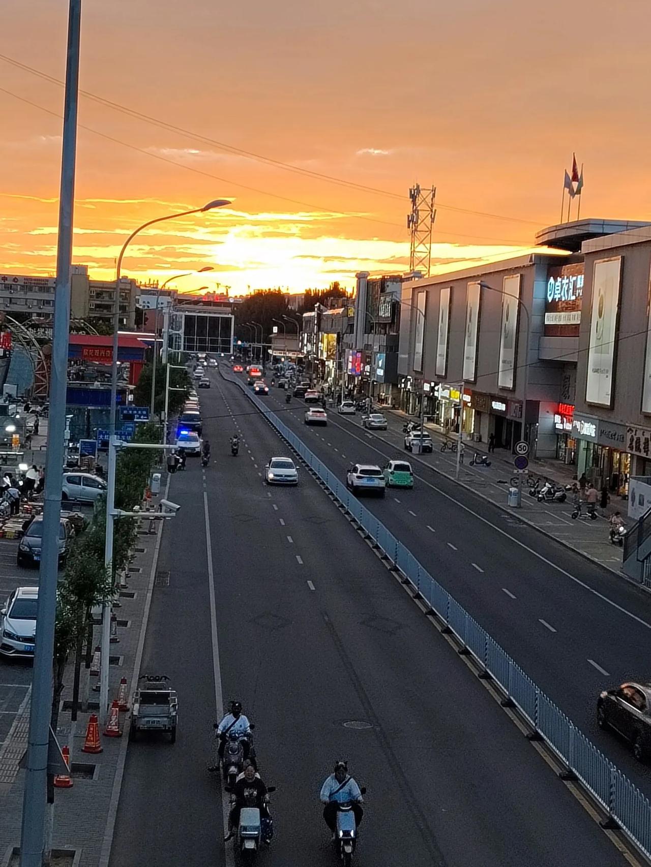 落日余晖映晚霞，一抹夕阳美如画。站在天桥上看街道的全景，只见灯火阑珊，车水马龙，