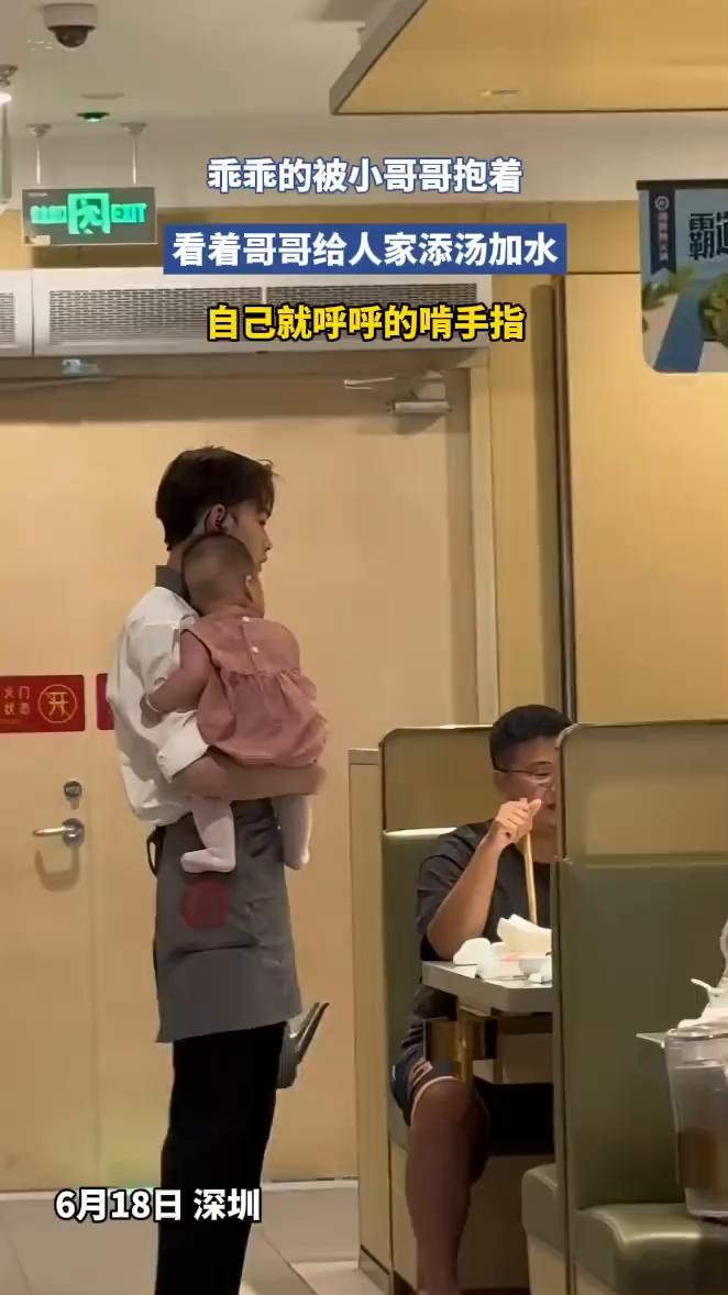 乖乖的被小哥哥抱着，看着哥哥给人家添汤加水，自己就呼呼的啃手指。
6月18日深圳
