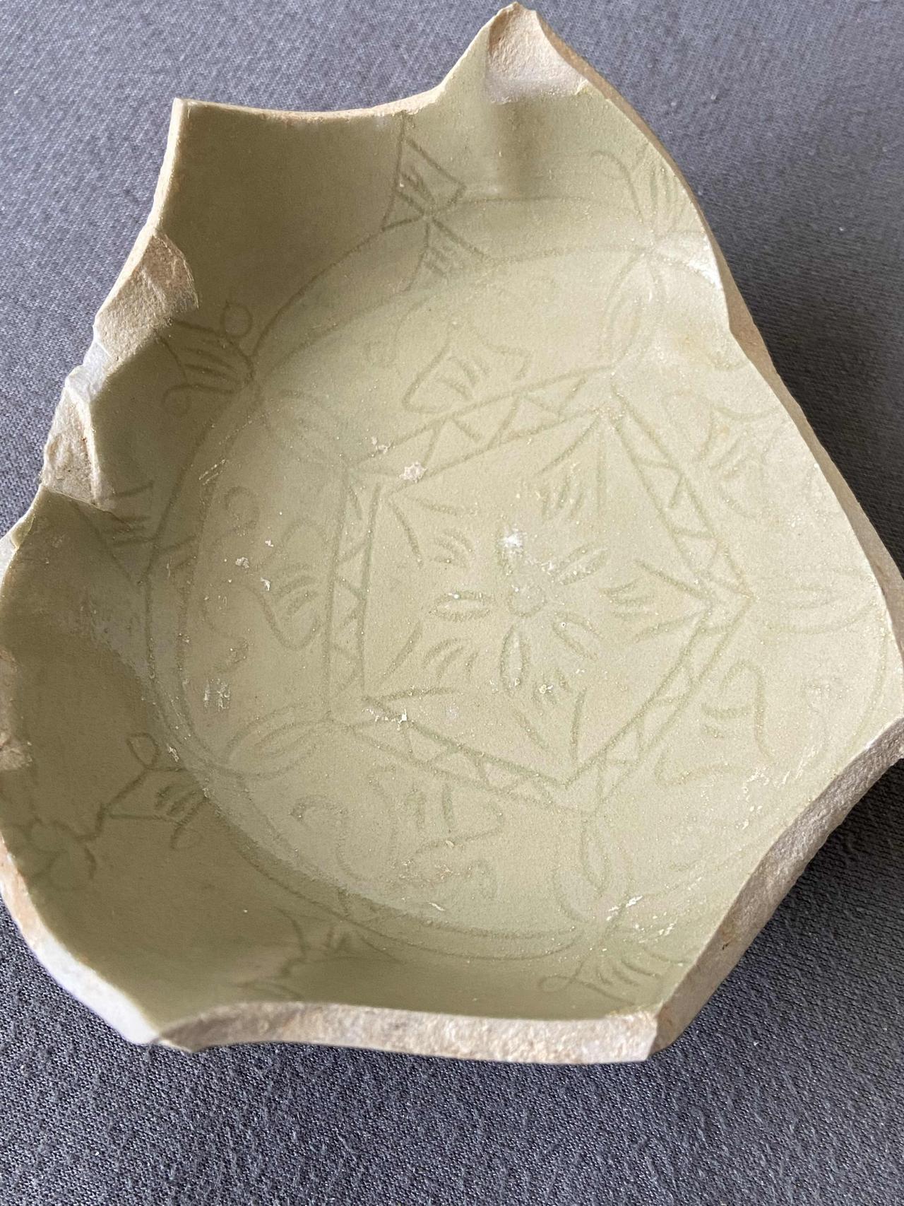 这是一件晚唐（唐宣宗大中年间，847-859年）越窑（上林湖窑场）青釉刻花盘残片