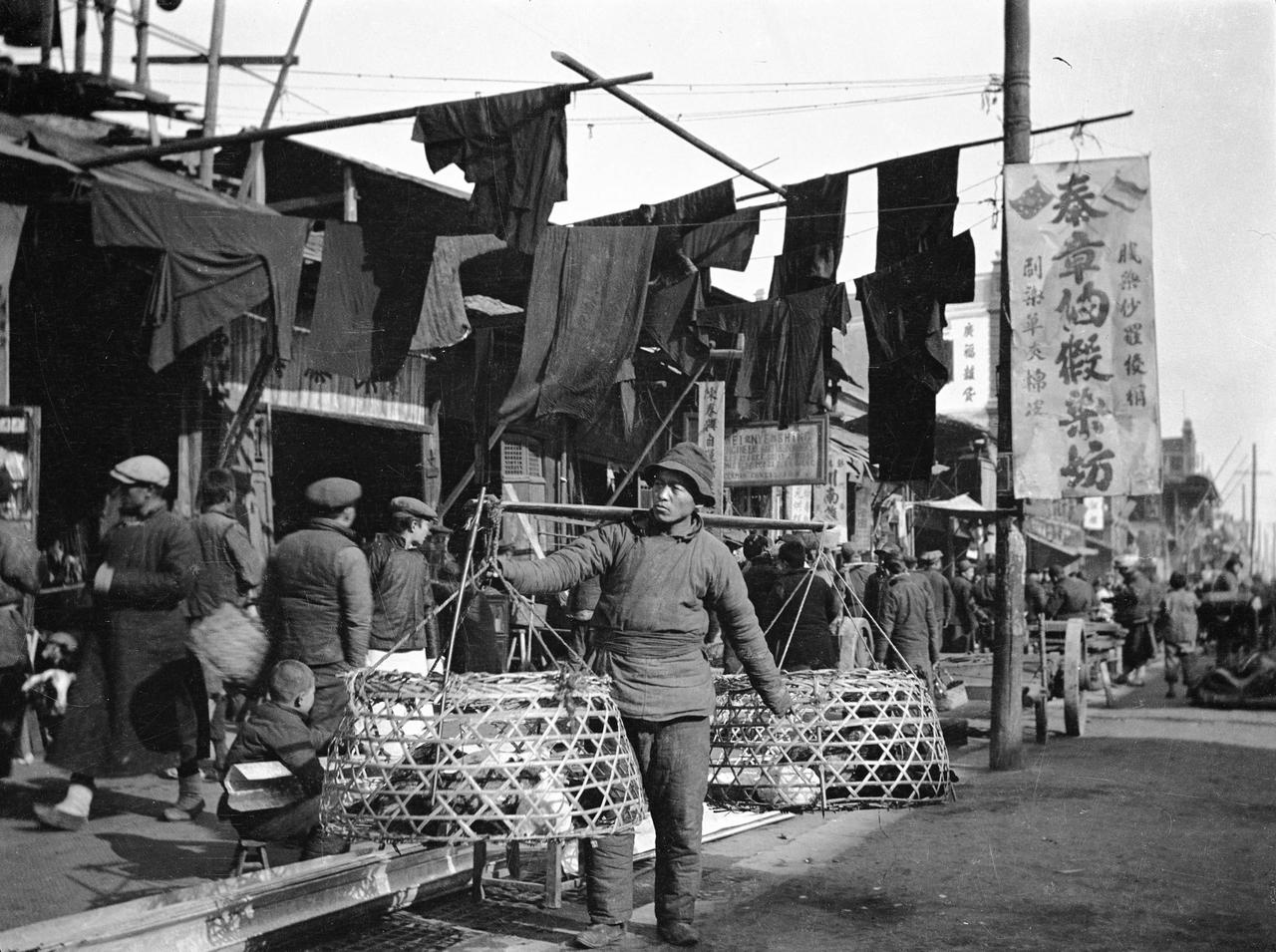 1914年的上海街头，一派鲜活的市井景象铺展开来。画面中央，一位小贩肩头稳稳扛着