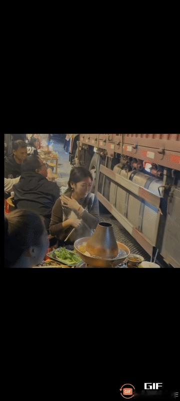 不得不佩服这名美女，在路边跟朋友吃火锅时，大货车擦边而过丝毫不慌，仍然跟同桌朋友