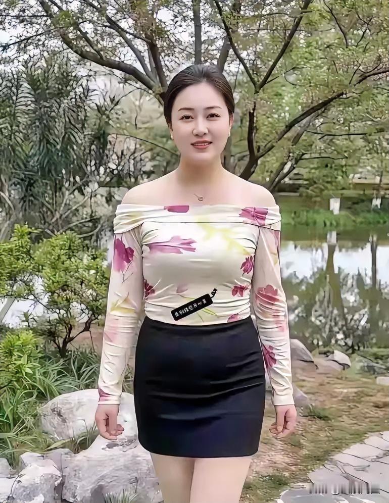 她穿着花衬衫和黑色短裙，站在公园里。