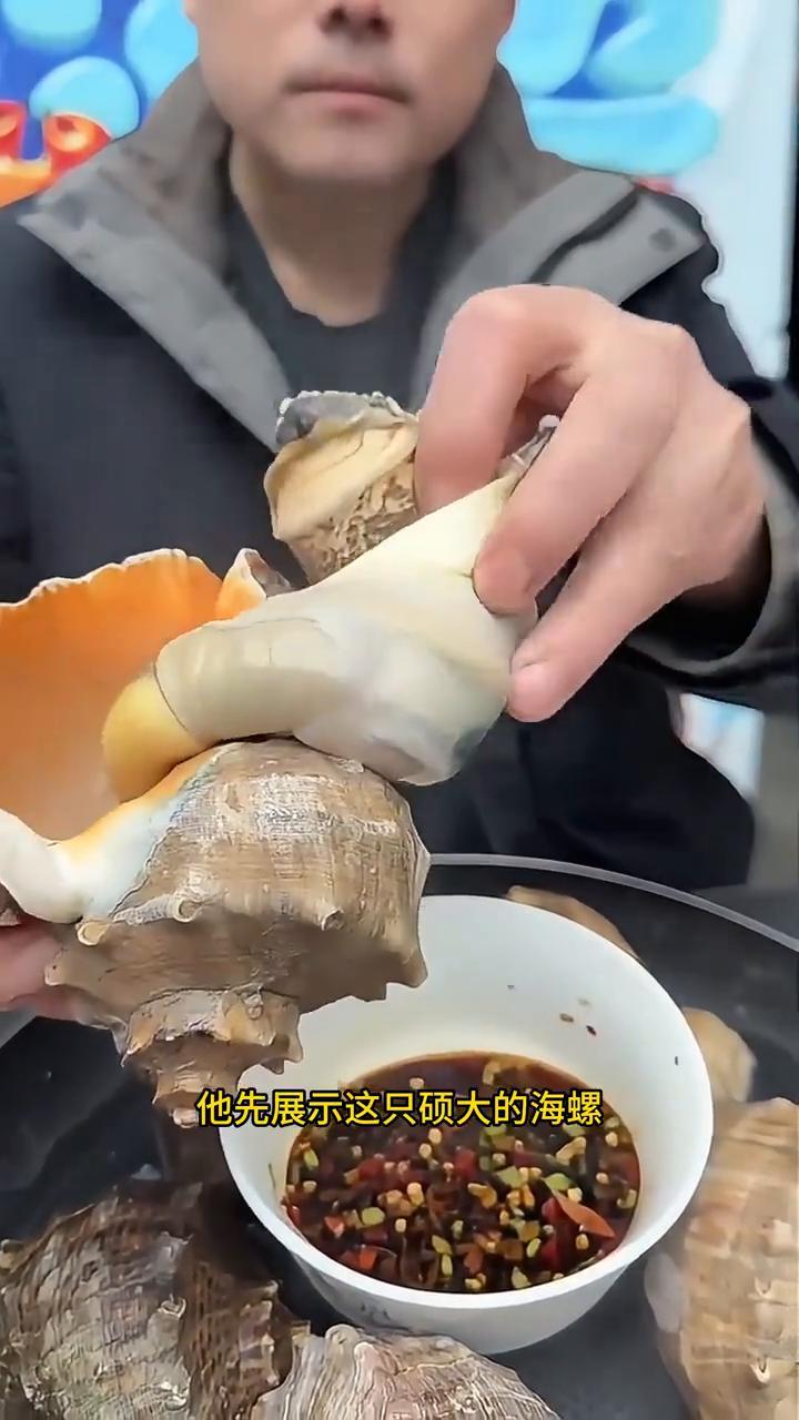 巨型海螺：美味处理与食用。
视频中一位美食爱好者正准备享用一道美味的海鲜，巨大的