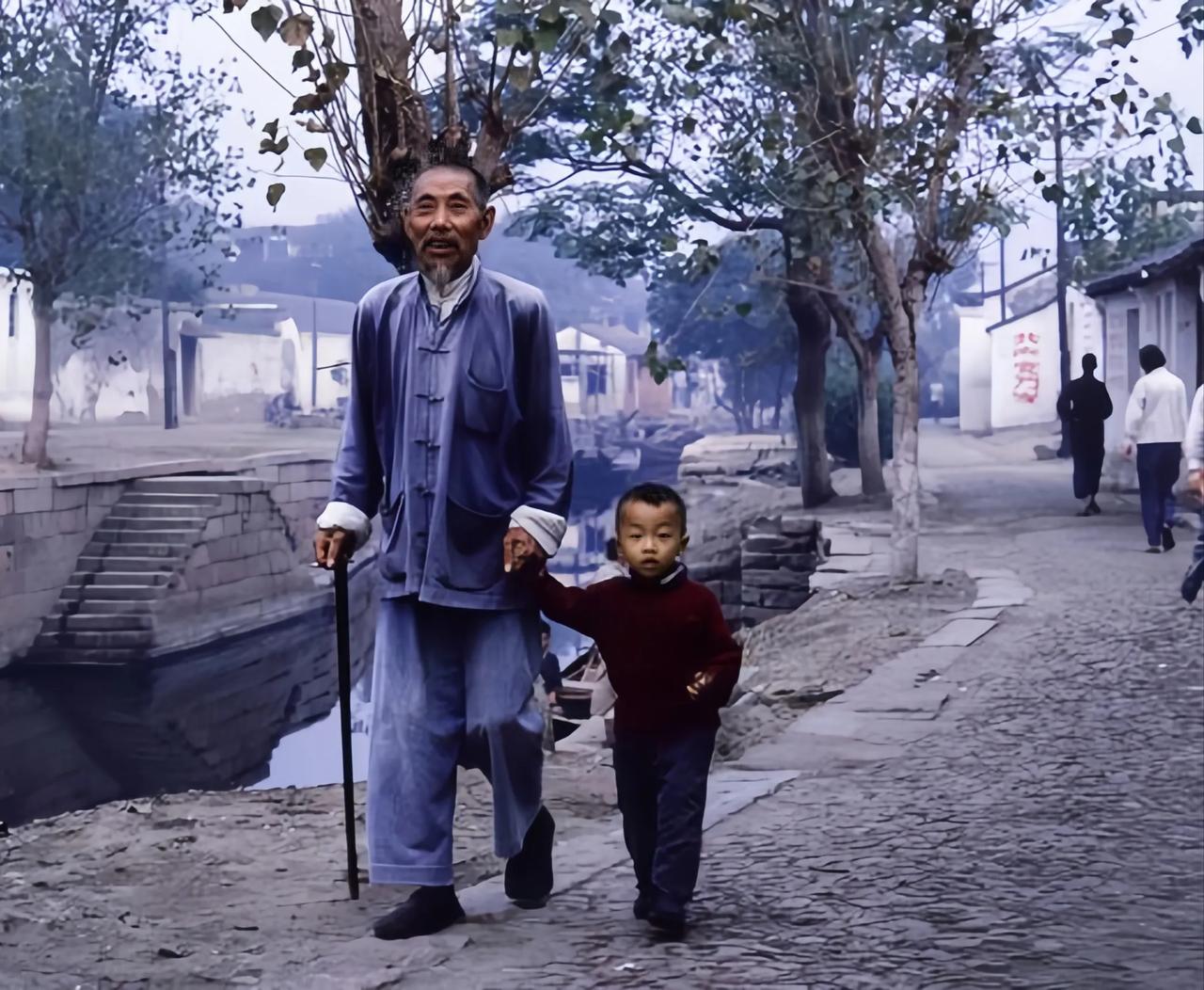 60年代，一位爷爷牵着小孙子在河边散步的合影。
看得出来爷爷非常疼爱孙子，两人在