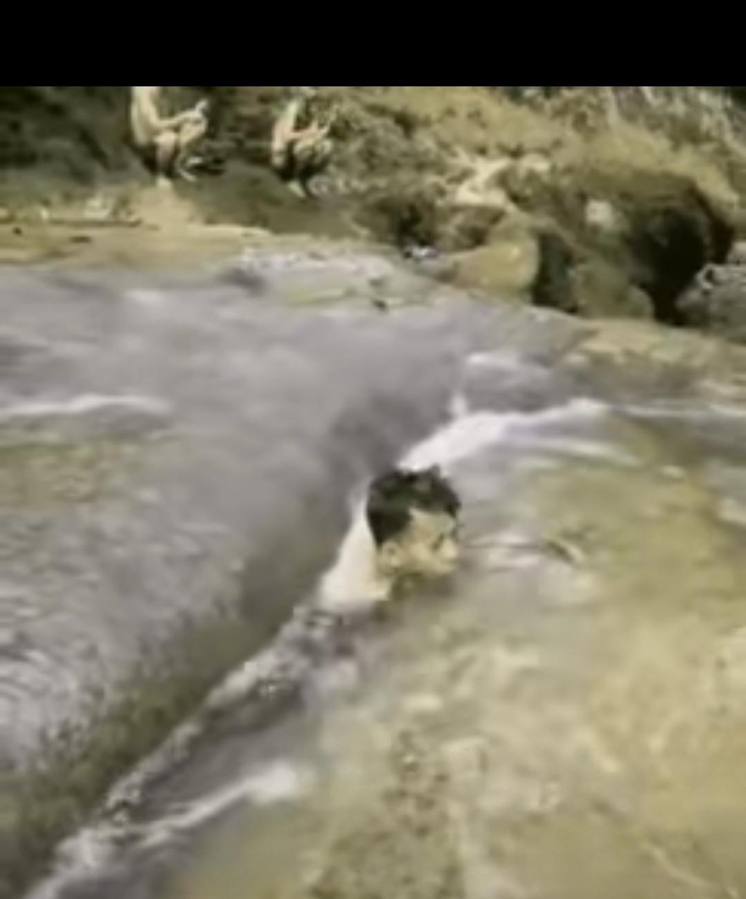 几名男子在山上的小溪里游泳，一名男子发现一块巨大的石头下面一条缝隙和一处水洞相连