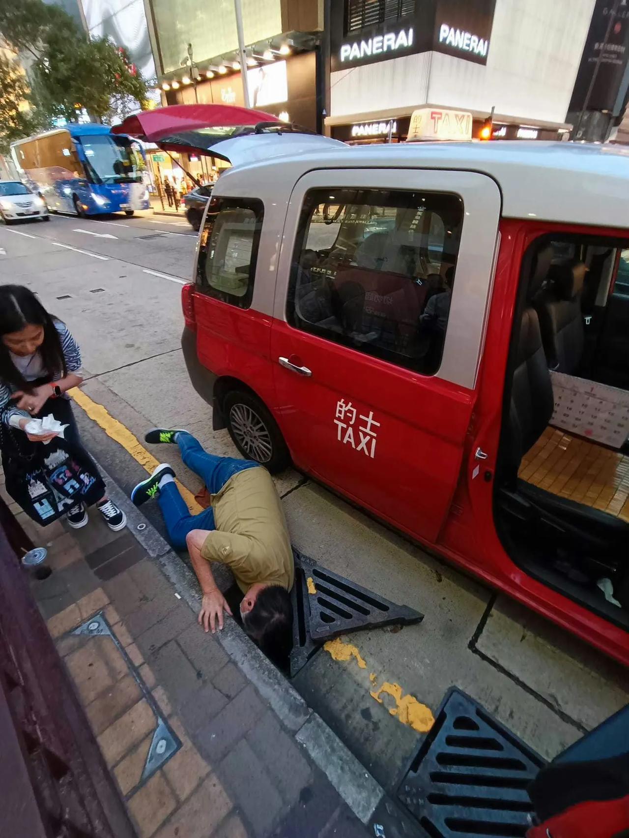 一名乘客下车，不小心把电话跌入水沟内。

司机大叔义不容辞下车，用力打开渠盖，趴