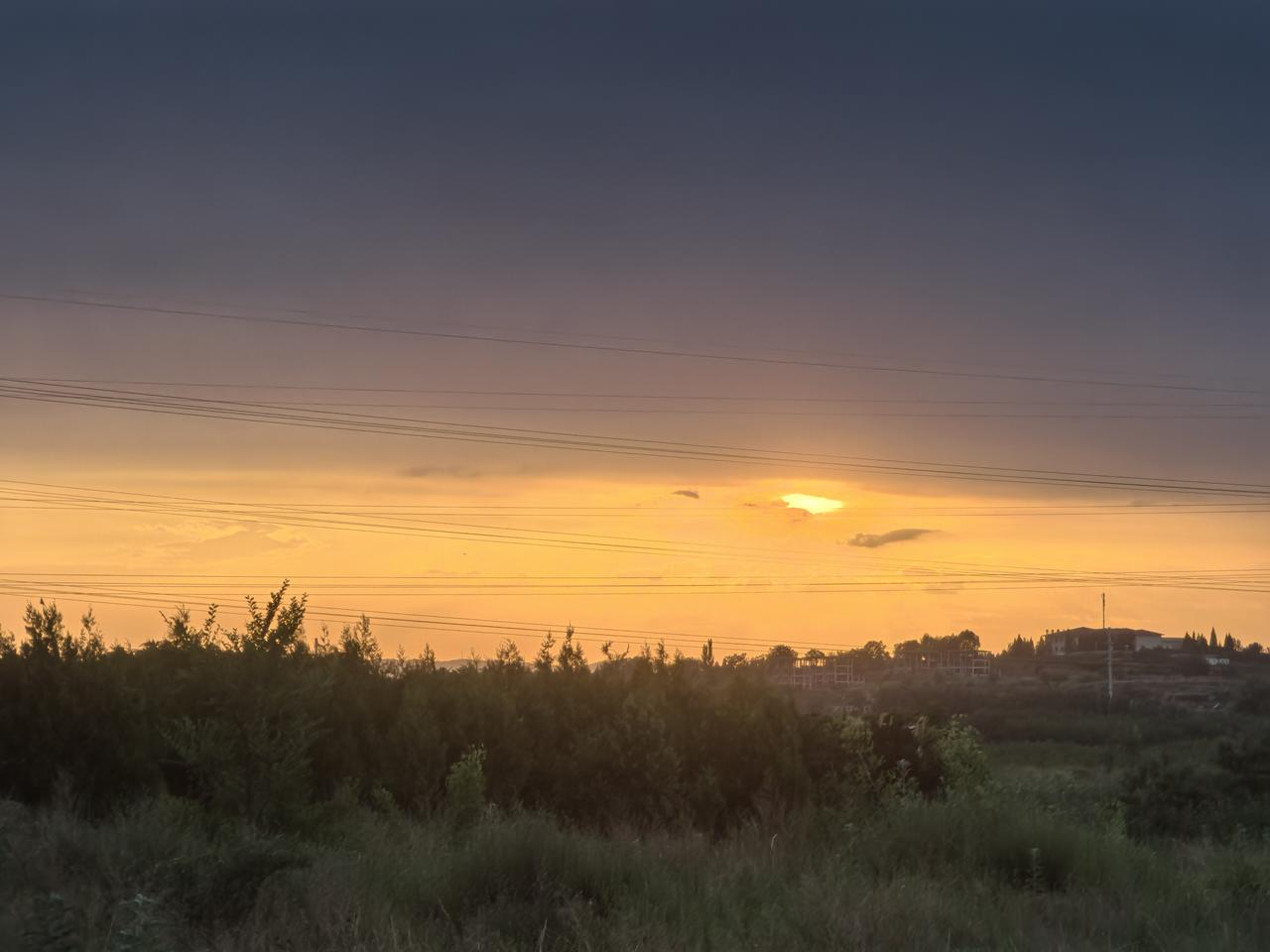 夕阳西下，田野静谧，电线横跨天际，自然与人类交织的美丽画面。