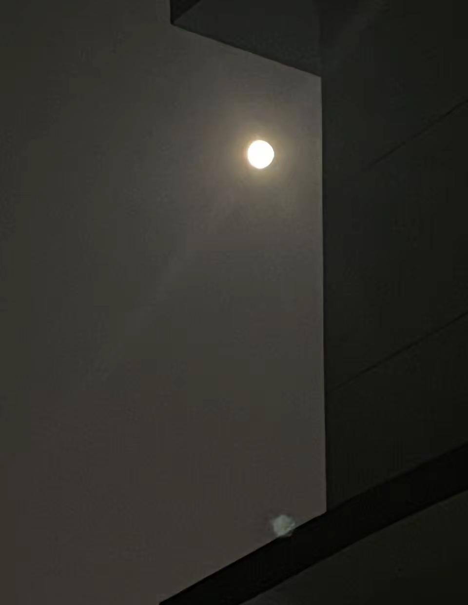夜色缓缓笼罩城市，楼房的棱角切割开灰蒙的夜空，一轮圆月静静悬在楼宇的缝隙之间。抬