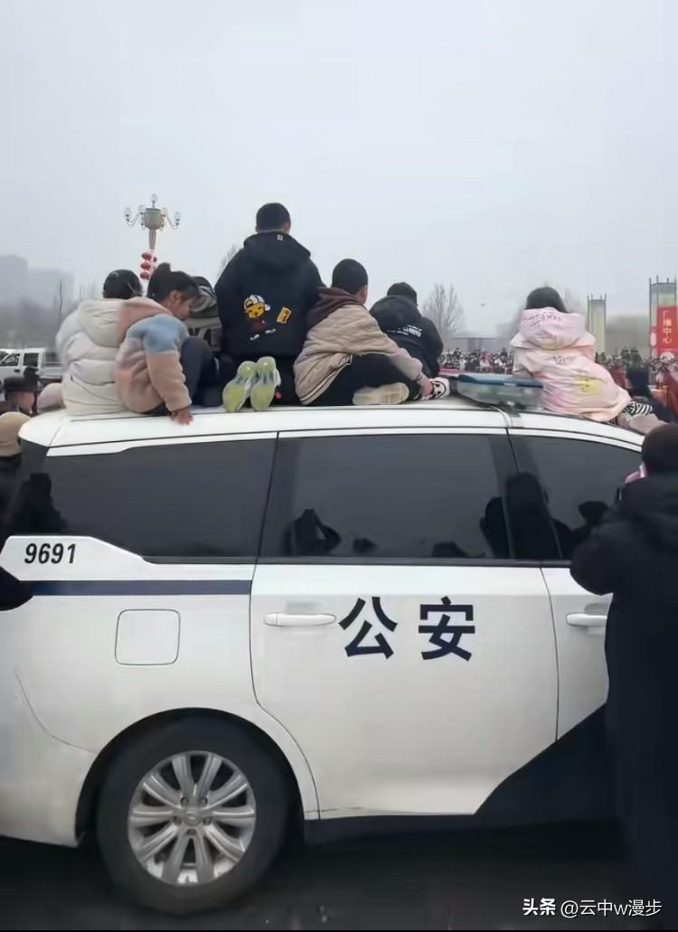 社火表演现场，一群小朋友为了观看更清楚，索性坐在了警车顶上。面对孩子们的天真举动