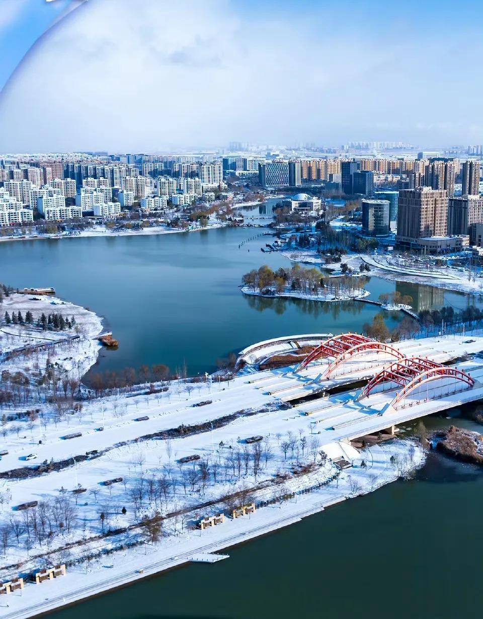 这是雪后的兰州新区栖霞湖俯拍，湖水美的冷艳，雪景白的凌冽，桥梁红的热烈……这样的