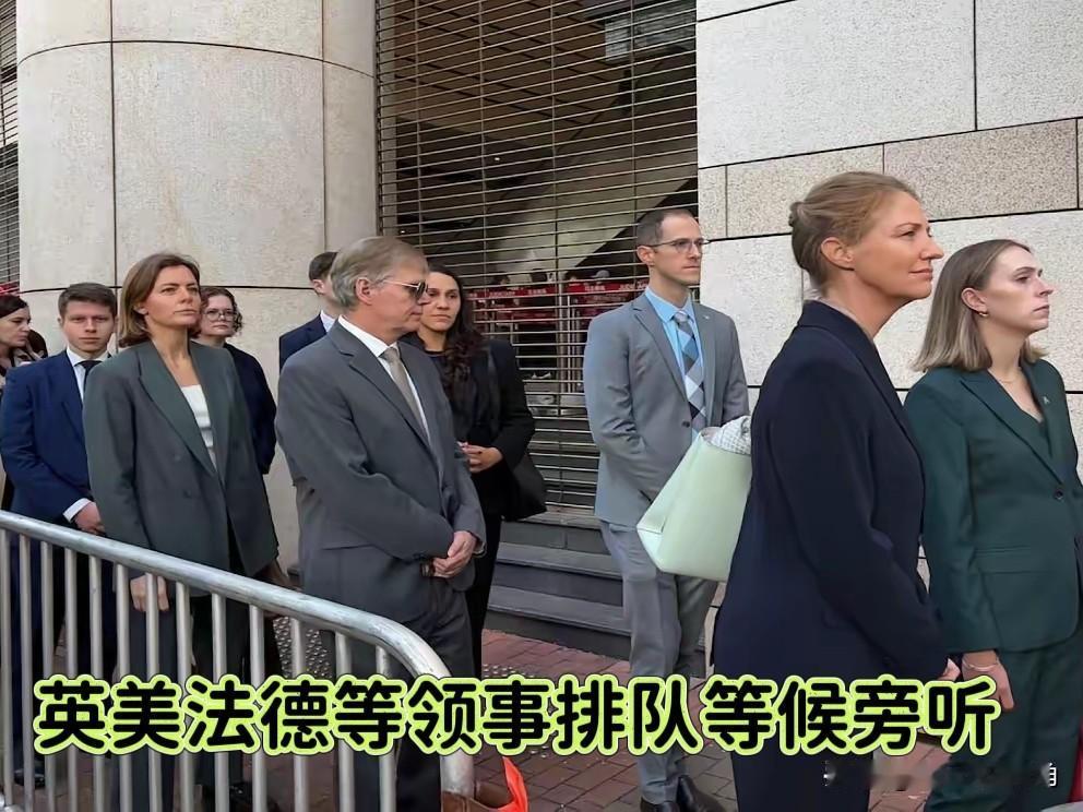 这画面真够魔幻的！
西九龙法院门口，竟然排起了一支“联合国”队伍，英、美、法、德