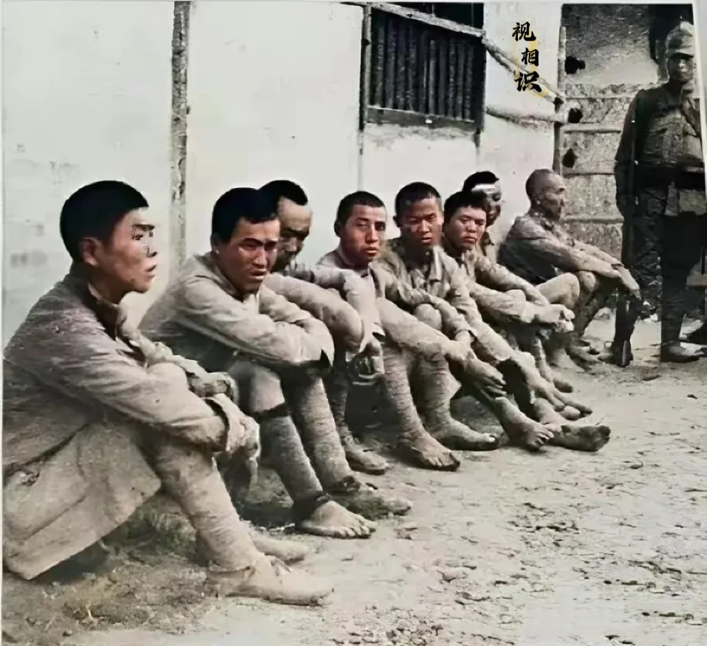 1937年，淞沪会战时期，一群被日军俘虏的战士们的照片，他们都被集中坐...