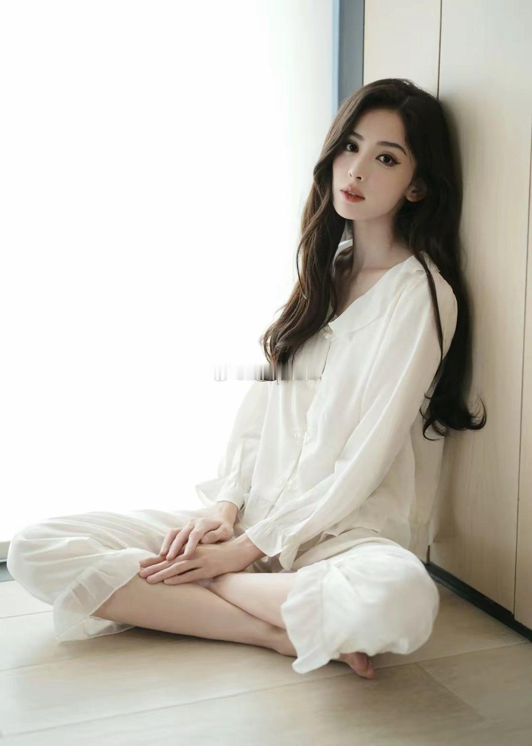 懒得理和张一龙分手传闻，古力娜扎穿着白色居家服，光着脚坐在地板上，卷发披肩，慵懒