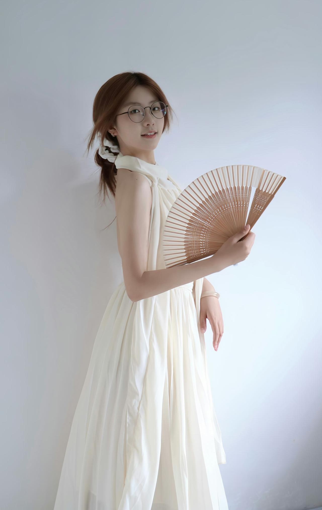 一袭素白长裙，一柄轻竹折扇，
眉眼温婉，书卷气悄然漫溢，
简约留白间，自带清雅氛