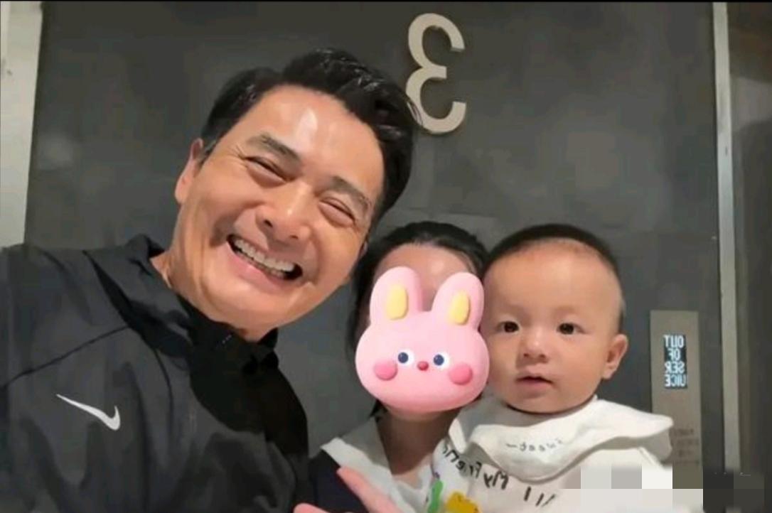 画面中的周润发略显发福，笑容灿烂，虽然染黑了头发，但依旧皮松肉垮，眼皮耷拉，眼袋