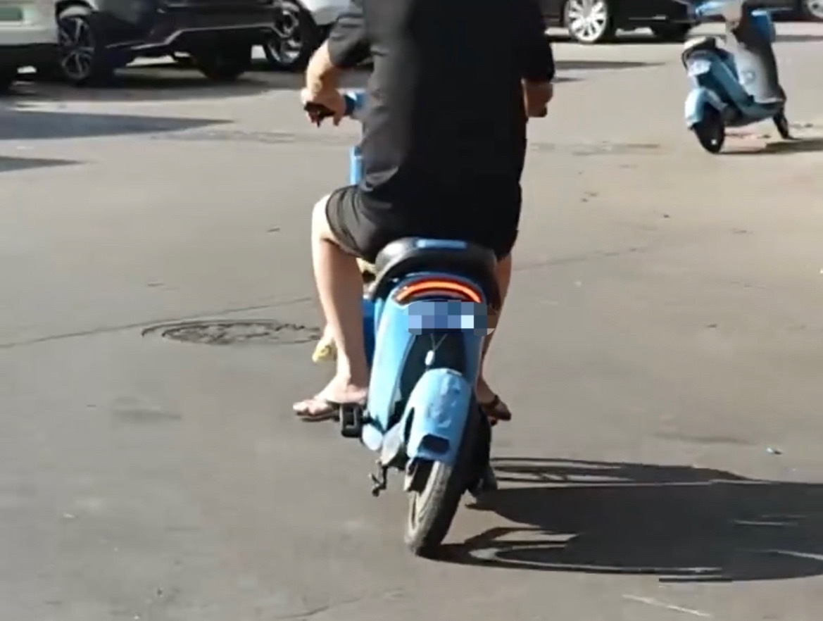 【玉林男子骑一辆车轮都歪的共享电车行驶】5月13日，有网友在玉林街头上看见一名男