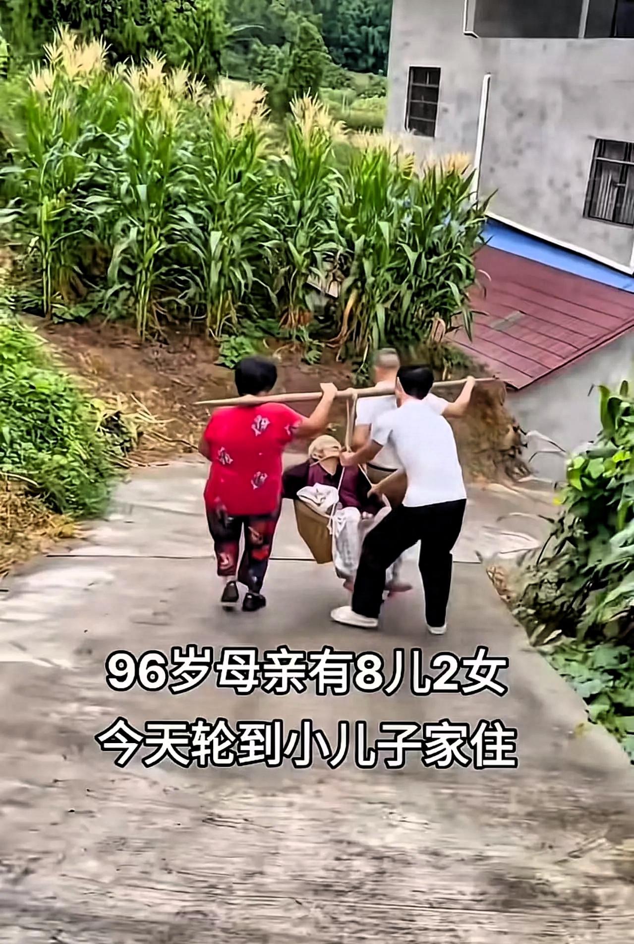 93岁老人有8儿2女，这次轮到小儿子家住，小儿子和儿媳拿着扁担将老人放入萝筐挑回