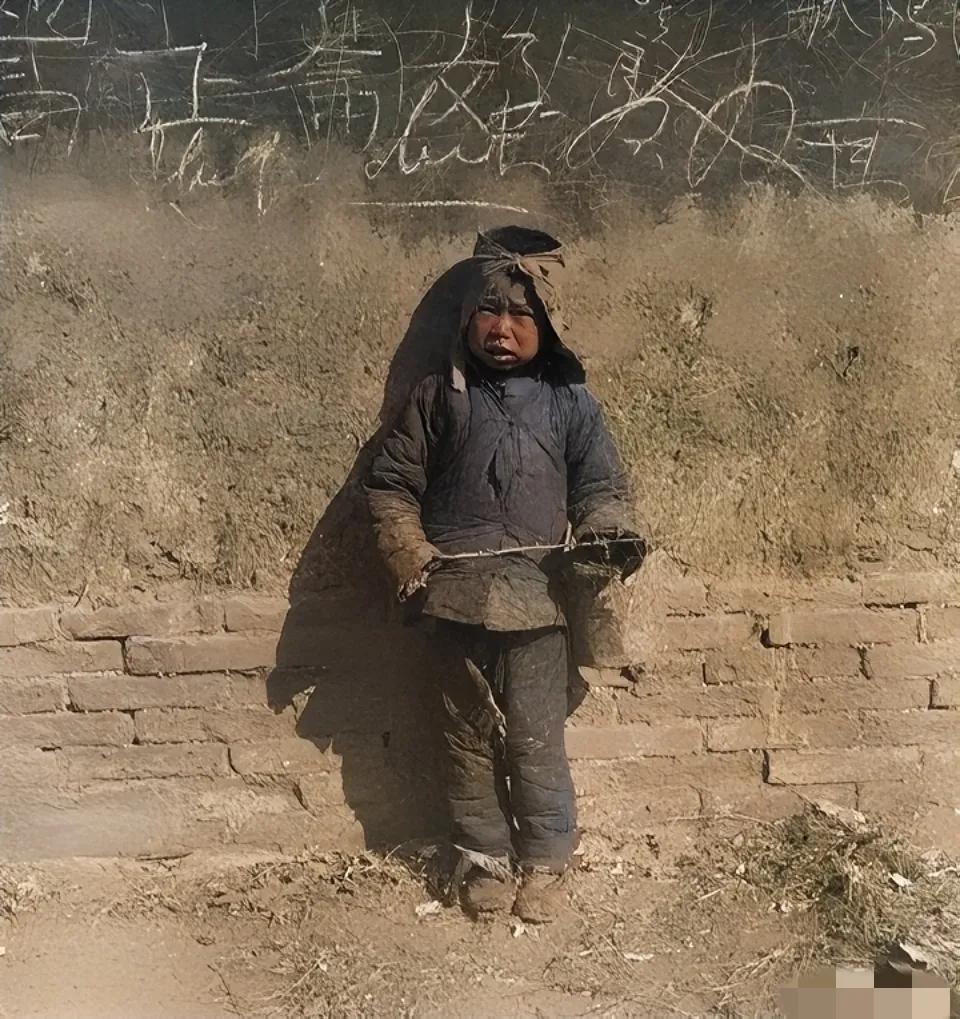 1920年，北平街头，一名乞讨的小男孩，照片中的他衣衫褴褛，手里拿着一根小树枝，